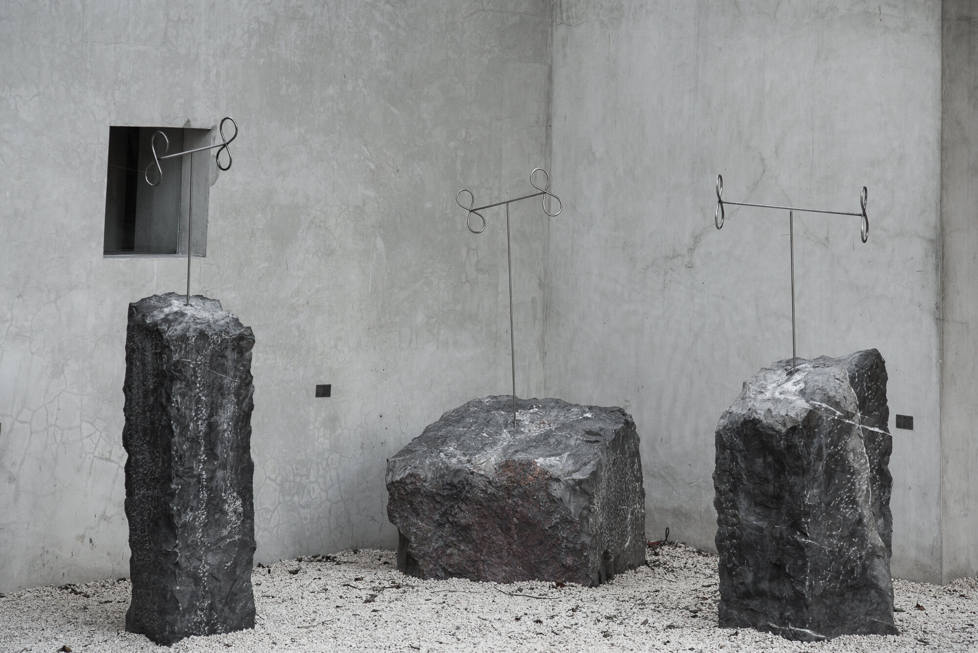 The three sculptures in a row against a concrete wall