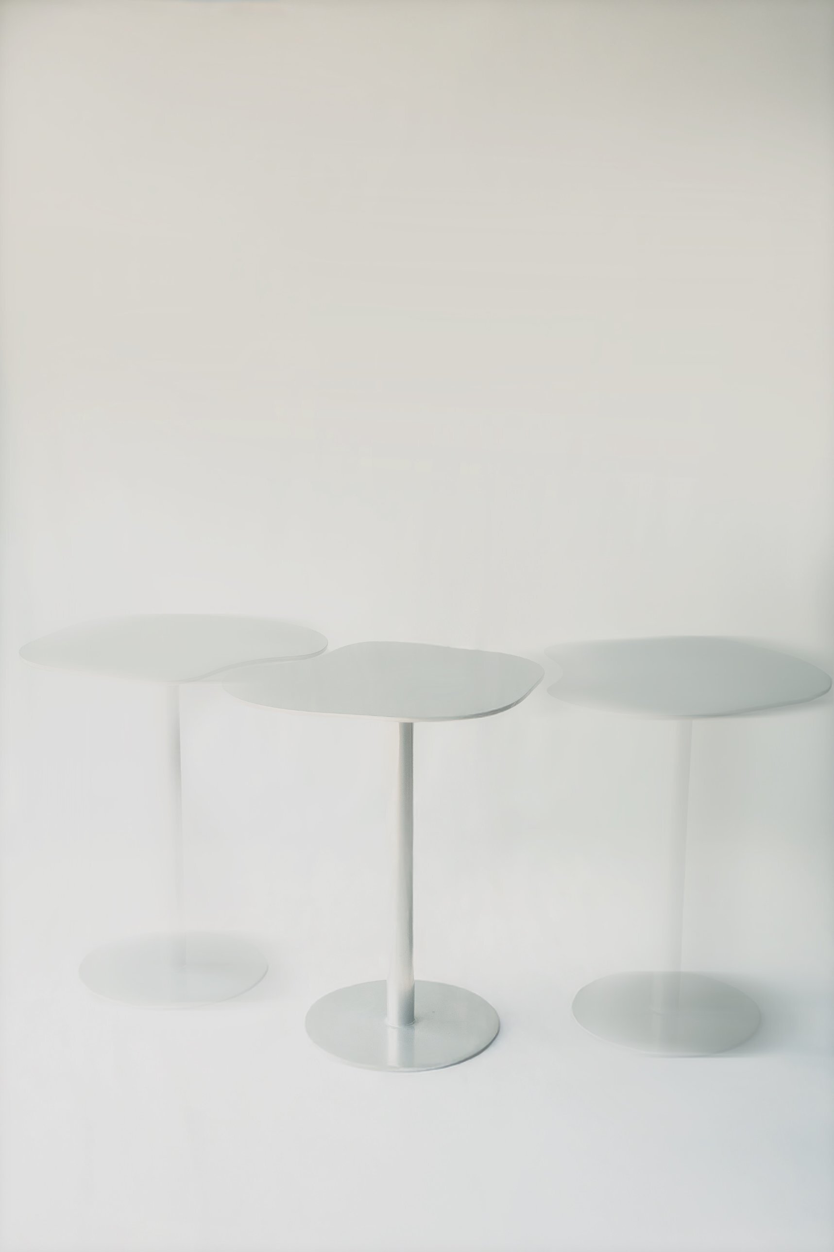 The three tables in a row, the outer two blurred as if dissolving into the white