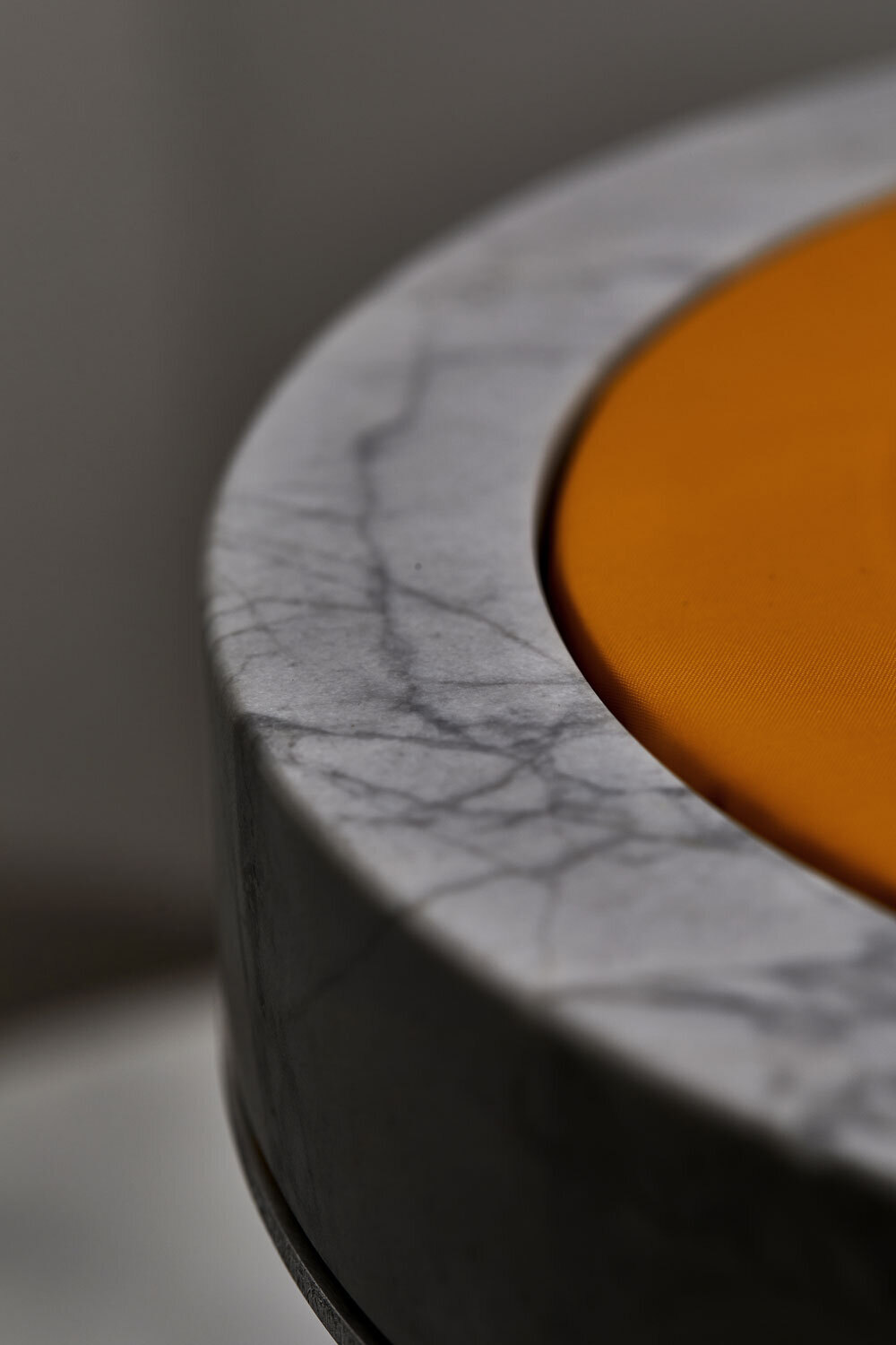 Veined marble edge meeting the orange disc